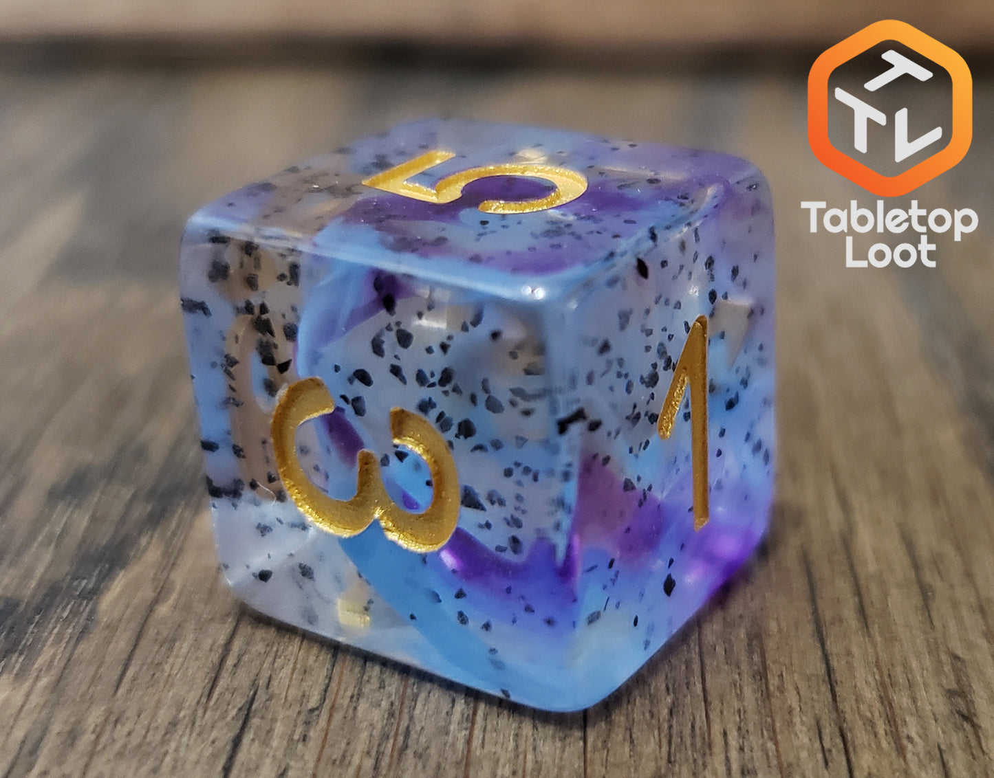 A close up of the D6 from the Infestation 7 piece dice set from Tabletop Loot with swirls of blue and purple and dark speckles suspended in a clear resin with gold numbering.