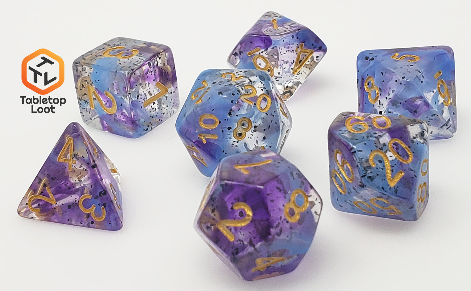 The Infestation 7 piece dice set from Tabletop Loot with swirls of blue and purple and dark speckles suspended in a clear resin with gold numbering.