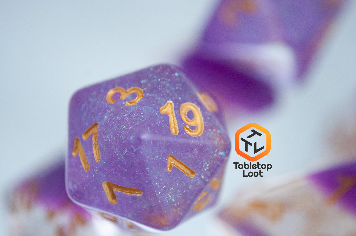 A close up of the D20 from the Gravitational Force 7 piece dice set from Tabletop Loot with a layer of light purple and clear glittery resin.
