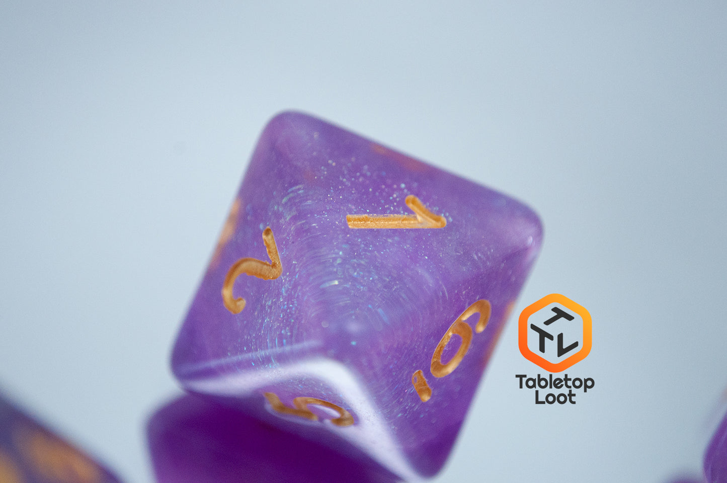 A close up of the D8 from the Gravitational Force 7 piece dice set from Tabletop Loot with a layer of light purple and clear glittery resin.