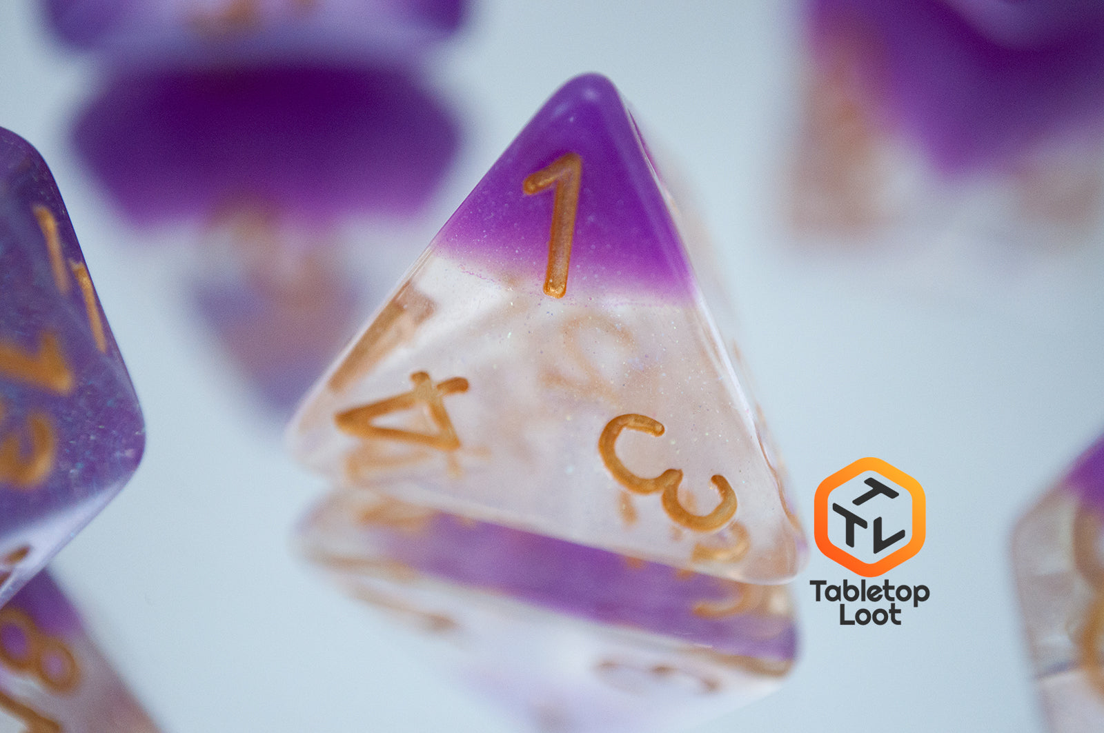 A close up of the D4 from the Gravitational Force 7 piece dice set from Tabletop Loot with a layer of light purple and clear glittery resin.