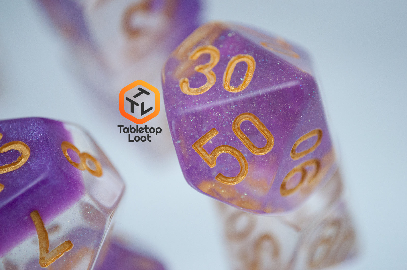 A close up of the percentile die from the Gravitational Force 7 piece dice set from Tabletop Loot with a layer of light purple and clear glittery resin.