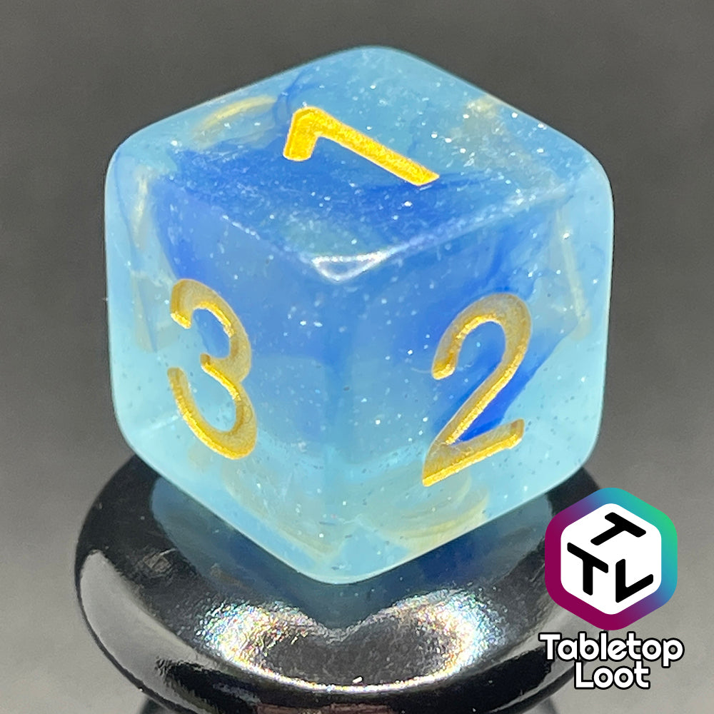 A close up of the D6 from the Water Genasi 7 piece dice set from Tabletop Loot with lots of glitter in two toned blue swirls and gold numbering.