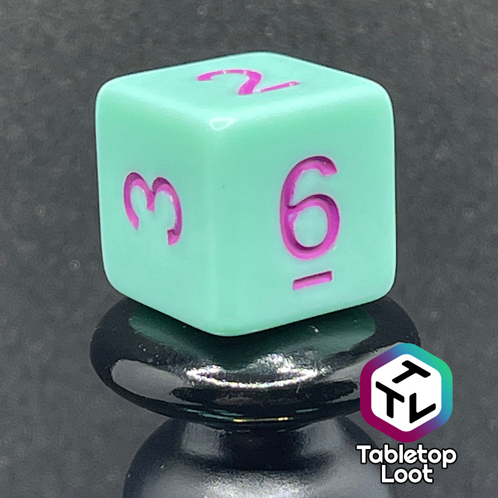A close up of the D6 from the Winterberry 7 piece dice set from Tabletop Loot with purple numbering on solid mint green dice.