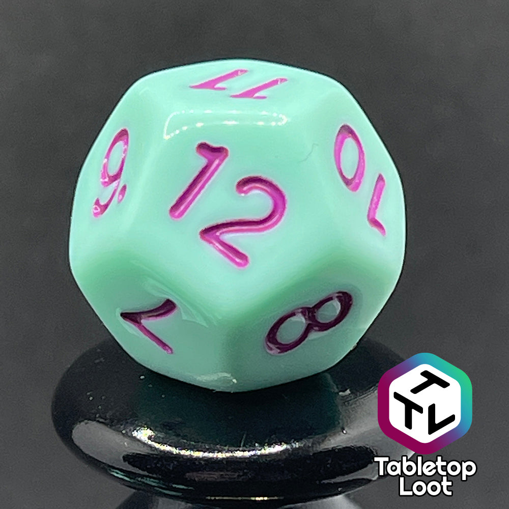 A close up of the D12 from the Winterberry 7 piece dice set from Tabletop Loot with purple numbering on solid mint green dice.