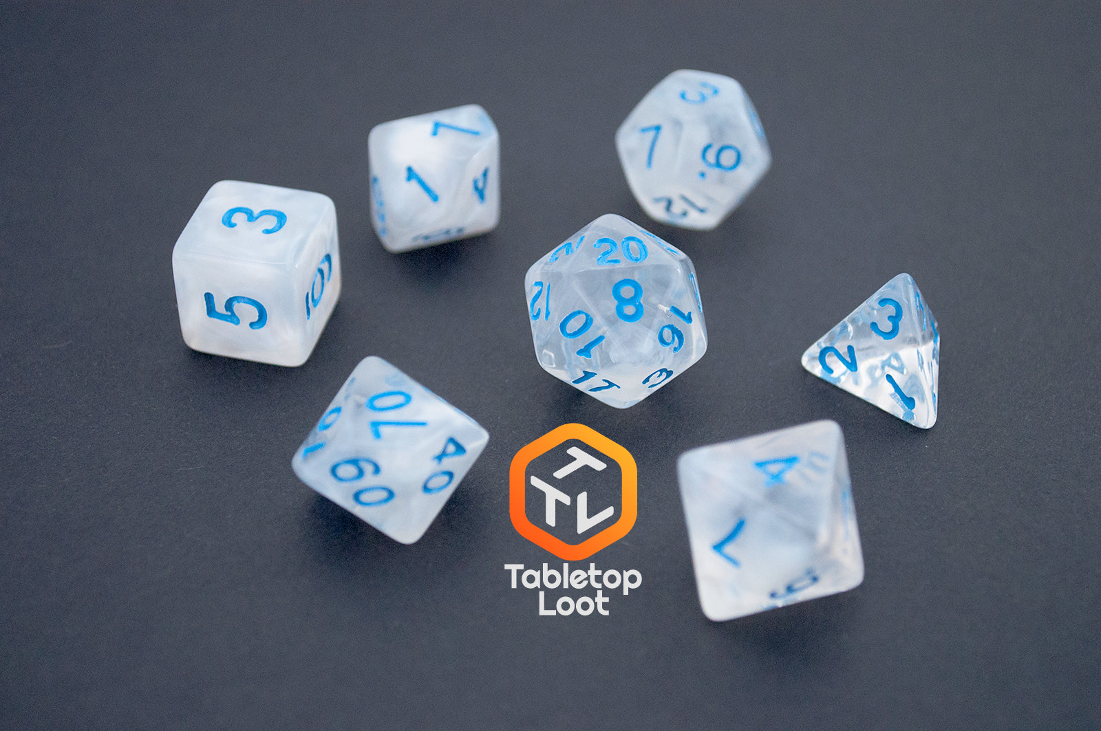 The Dinneshere 7 piece dice set from Tabletop Loot with wispy white swirls and blue numbering.