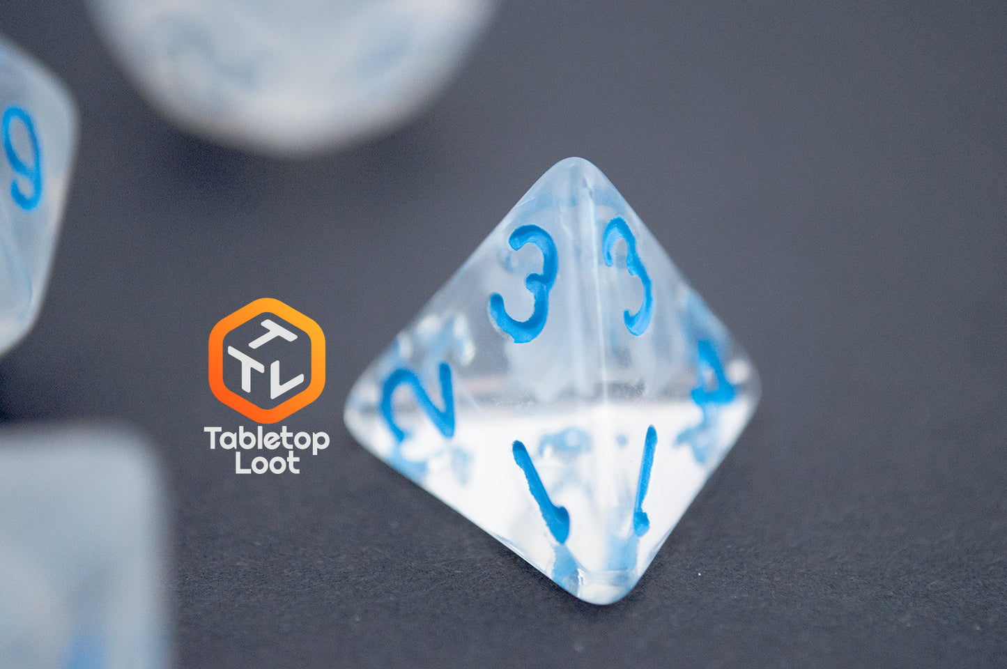 A close up of the D4 from the Dinneshere 7 piece dice set from Tabletop Loot with wispy white swirls and blue numbering.