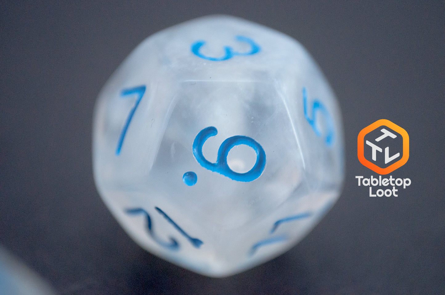 A close up of the D12 from the Dinneshere 7 piece dice set from Tabletop Loot with wispy white swirls and blue numbering.
