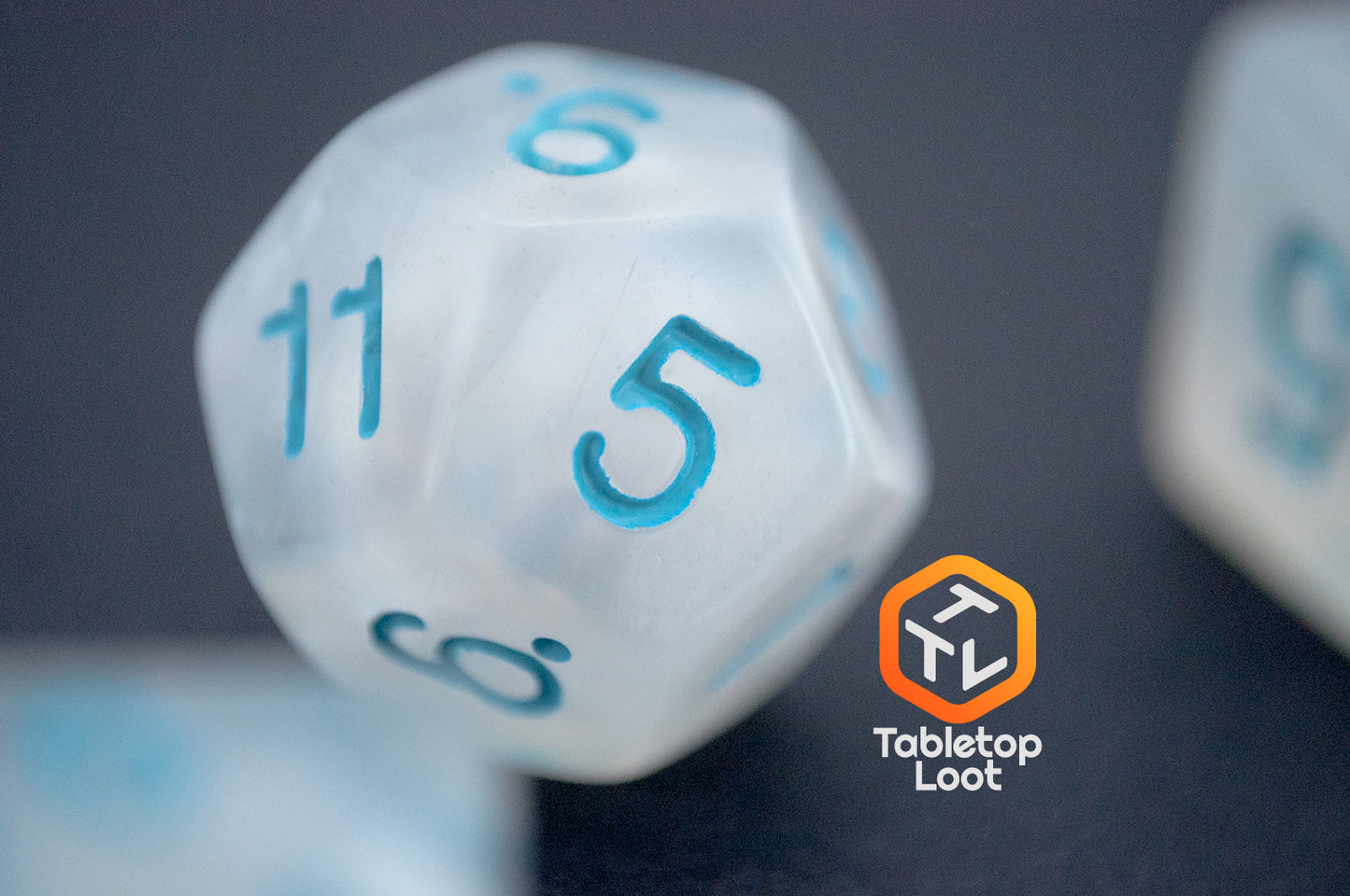 A close up of the D12 from the Dinneshere 7 piece dice set from Tabletop Loot with wispy white swirls and blue numbering.