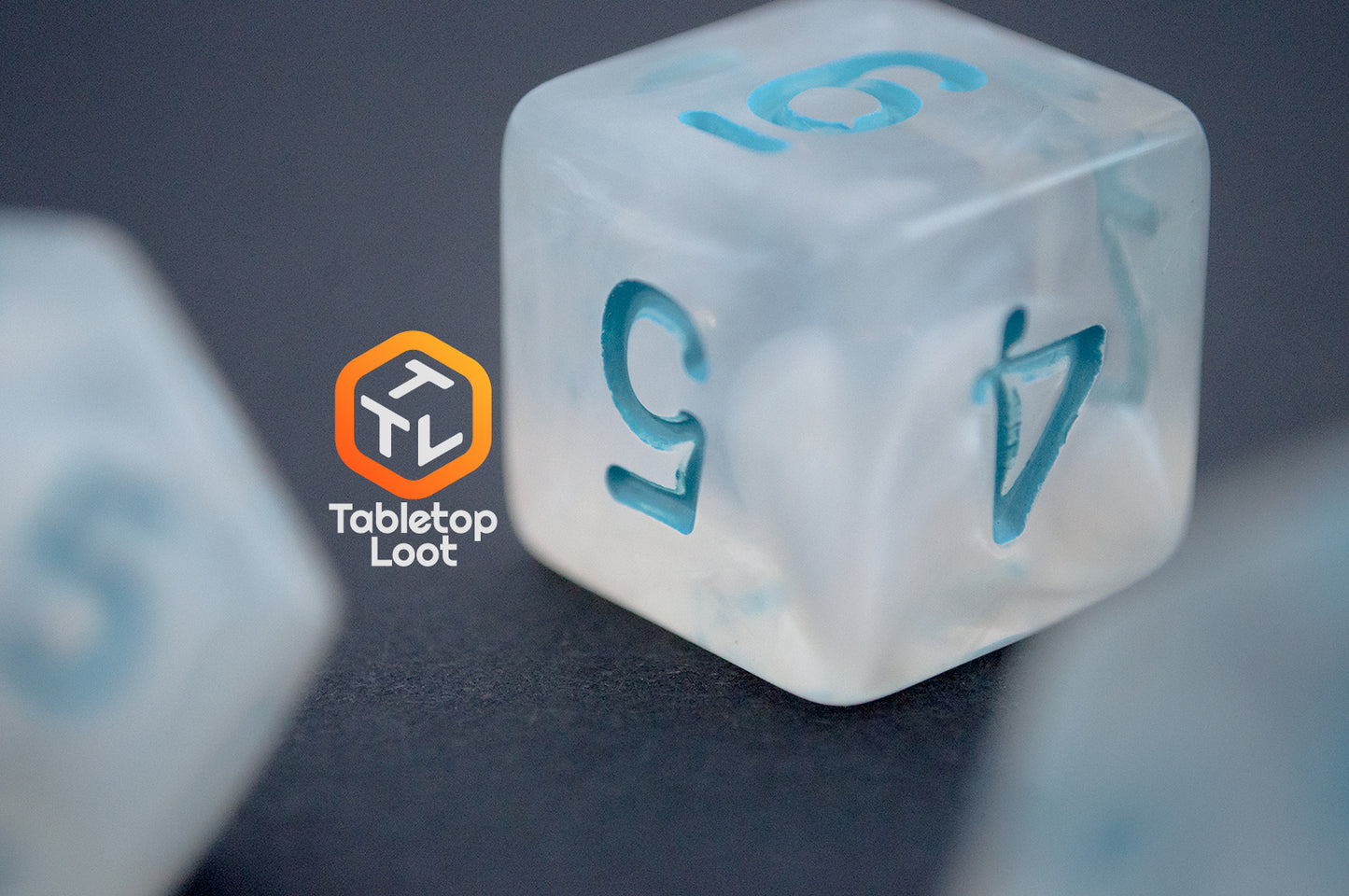 A close up of the D6 from the Dinneshere 7 piece dice set from Tabletop Loot with wispy white swirls and blue numbering.