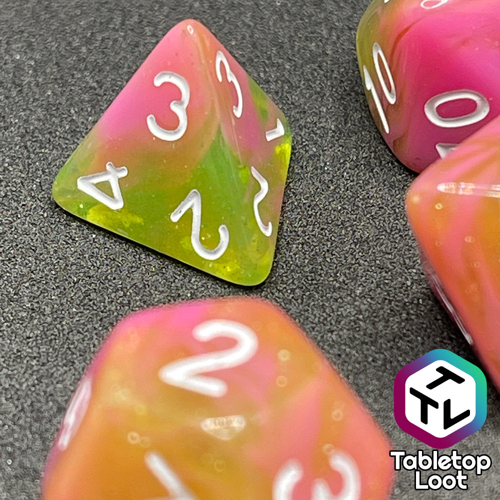 A close up of the D4 from the Wither and Bloom 7 piece dice set with bright pink and glittery green swirls and white numbering.
