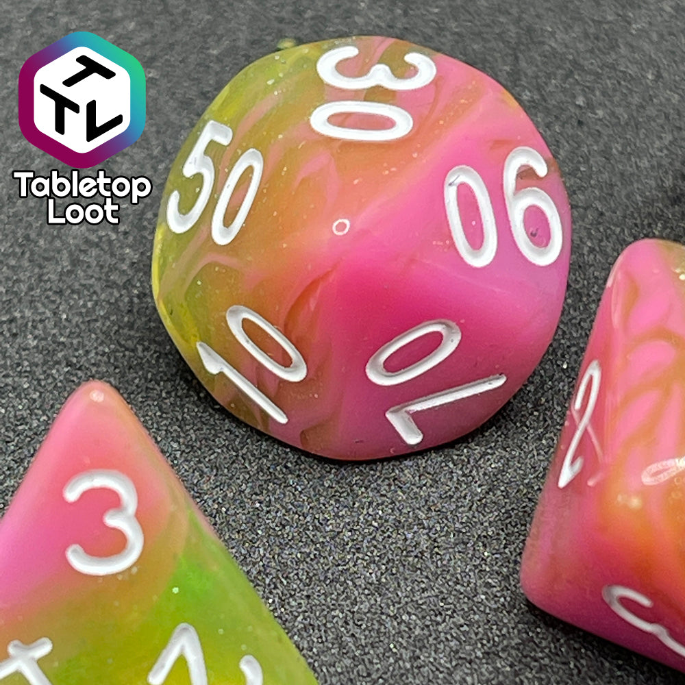 A close up of the percentile die from the Wither and Bloom 7 piece dice set with bright pink and glittery green swirls and white numbering.