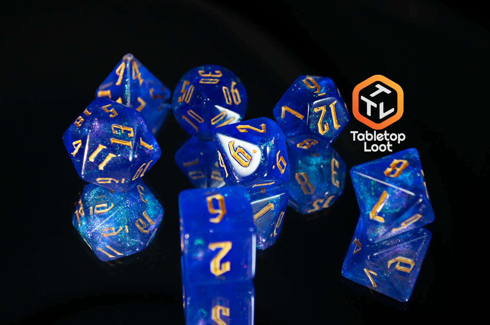 The Wizard's Script 7 piece dice set from Tabletop Loot with bright blue shimmery resin and gold numbering.