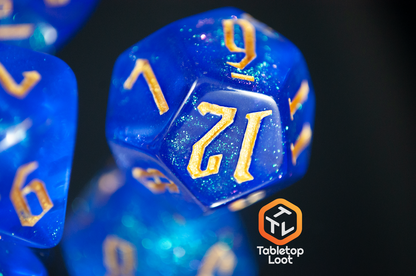 A close up of the D12 from the Wizard's Script 7 piece dice set from Tabletop Loot with bright blue shimmery resin and gold numbering.