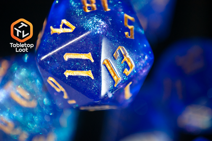 A close up of the D20 from the Wizard's Script 7 piece dice set from Tabletop Loot with bright blue shimmery resin and gold numbering.