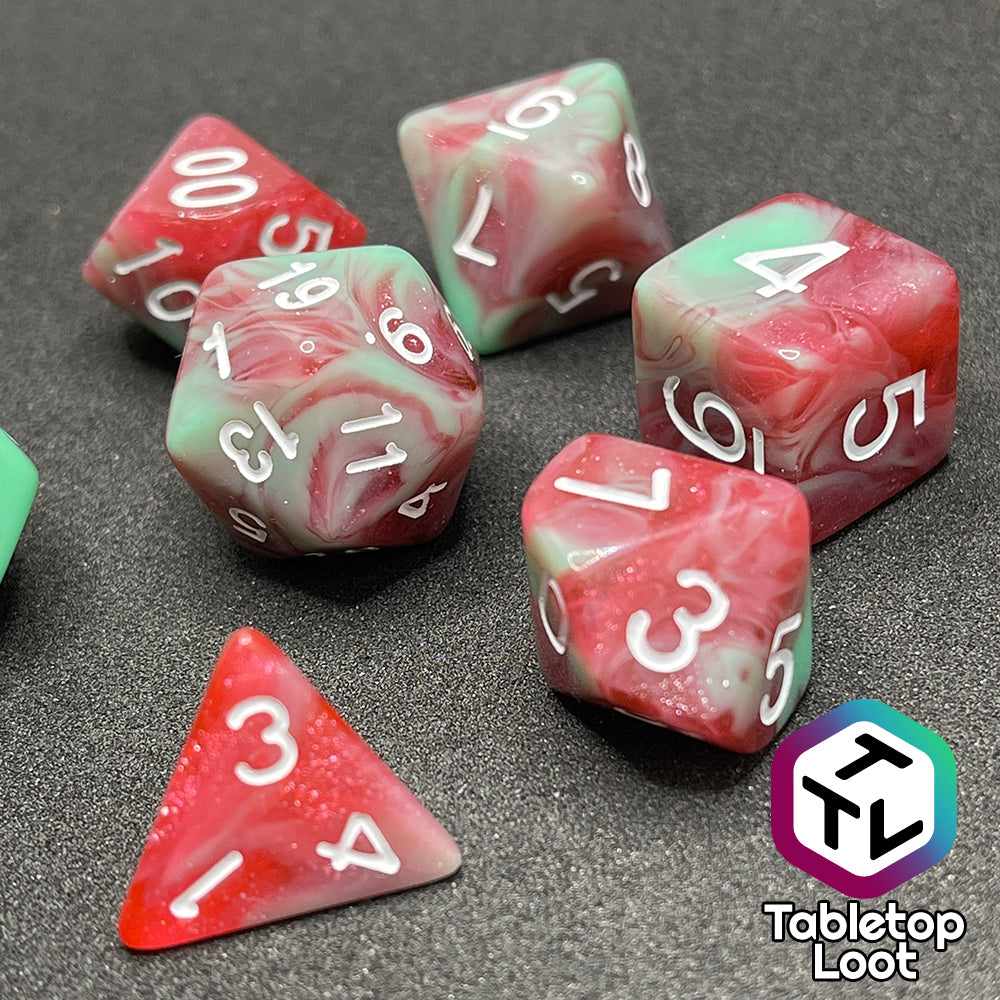 A close up of the Zombies 7 piece dice set from Tabletop Loot with sickly green and glittering red swirls and white numbering.
