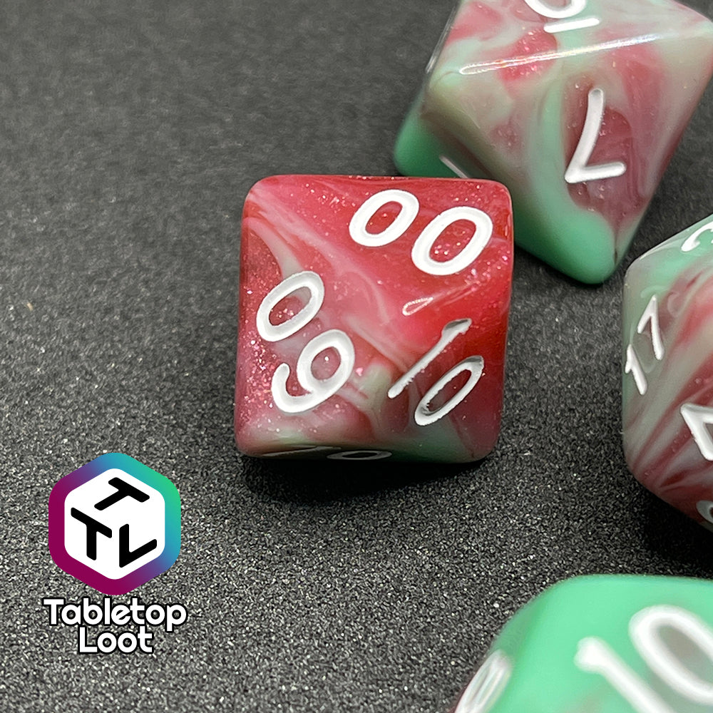 A close up of the percentile die from the Zombies 7 piece dice set from Tabletop Loot with sickly green and glittering red swirls and white numbering.
