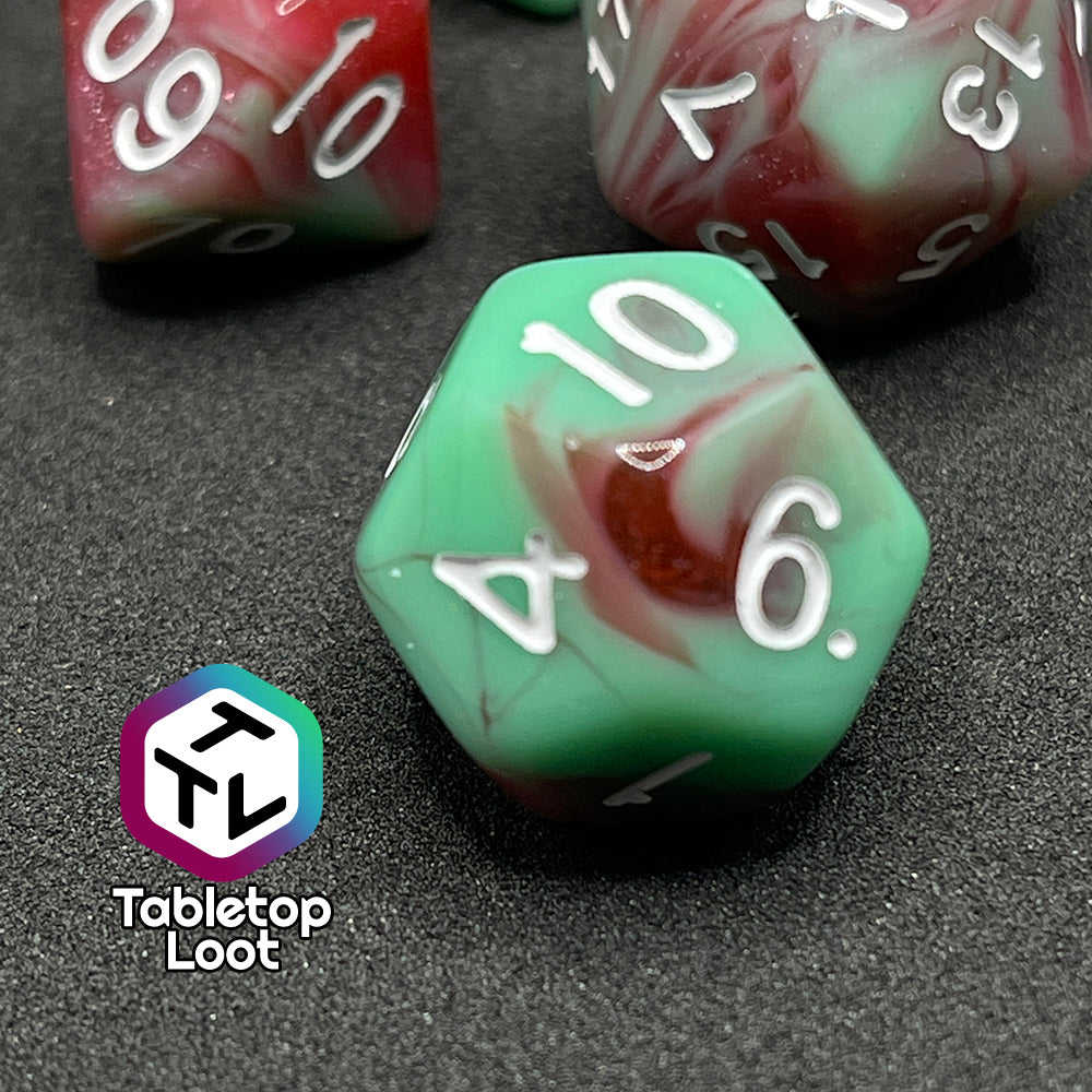 A close up of the D12 from the Zombies 7 piece dice set from Tabletop Loot with sickly green and glittering red swirls and white numbering.