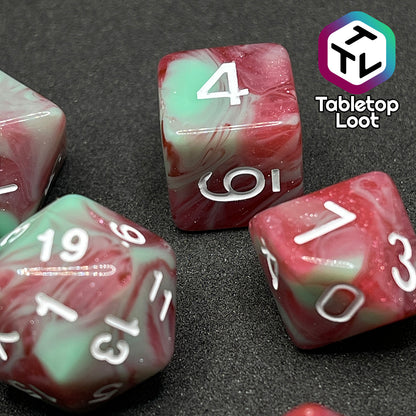 A close up of the D6 and D10 from the Zombies 7 piece dice set from Tabletop Loot with sickly green and glittering red swirls and white numbering.
