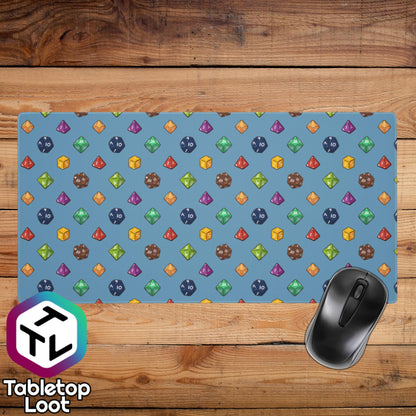 A wide 36 by 18 inch desk and mouse pad has a polyhedral dice pattern in red, brown, yellow, teal, blue, and purple on a blue background.