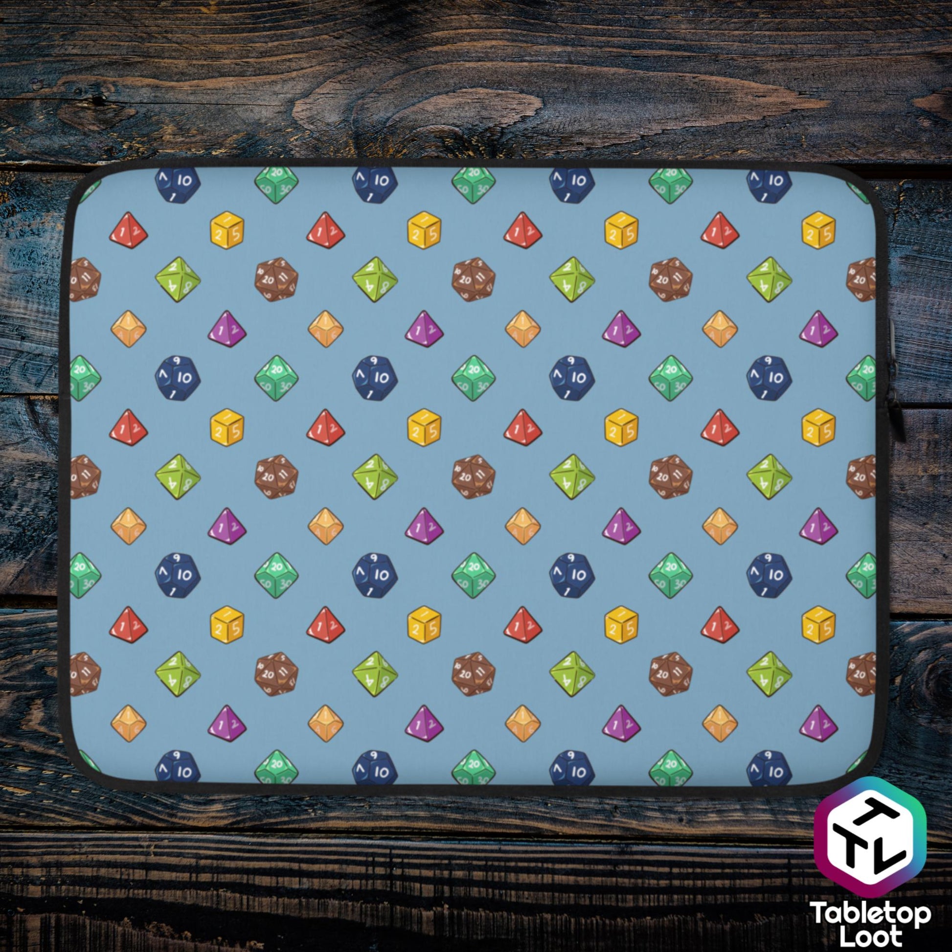 A 15 inch zippered laptop sleeve has a polyhedral dice pattern in red, brown, yellow, teal, blue, and purple on a blue background.