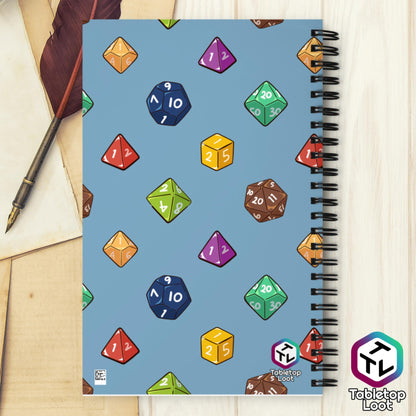 The back of the spiral notebook continuing the polyhedral dice pattern in red, brown, yellow, teal, blue, and purple on a blue background and the Tabletop Loot logo.
