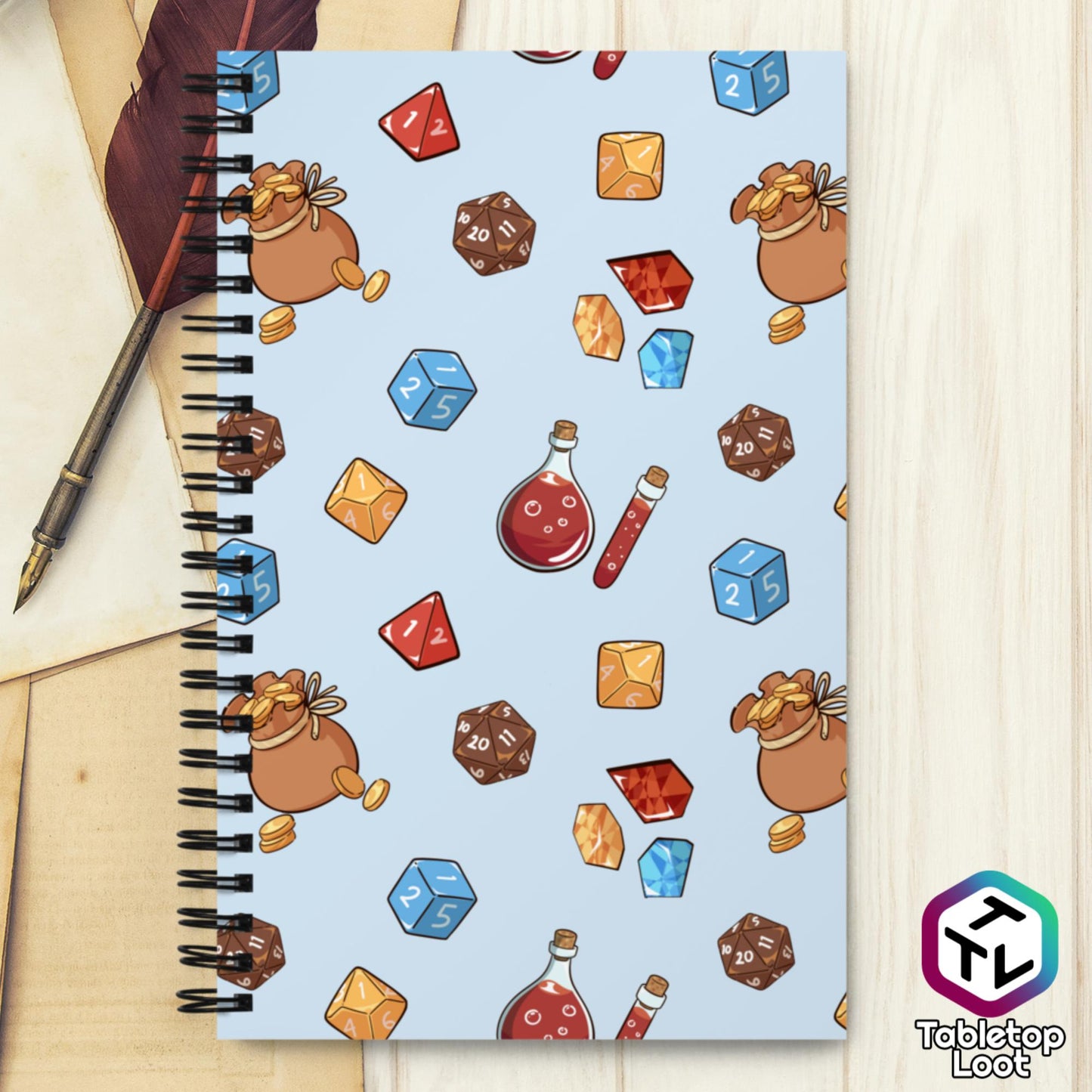 A spiral notebook from Tabletop Loot with a pattern of dice, gems, potions, and sacks of gold on a blue background.